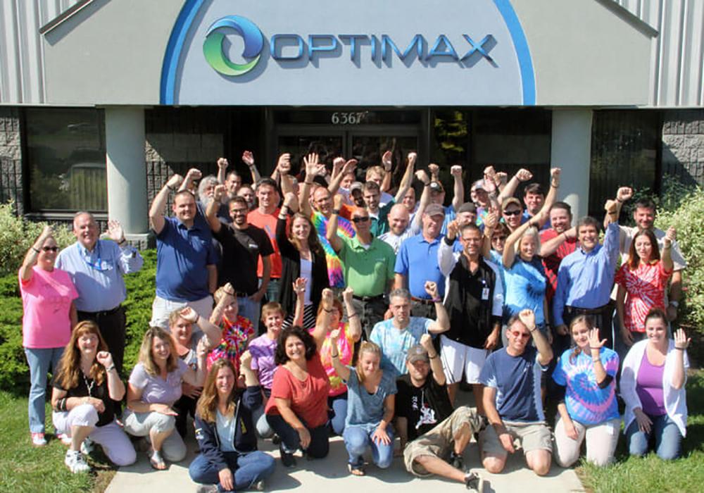 Optimax group gathered for photo outside of building